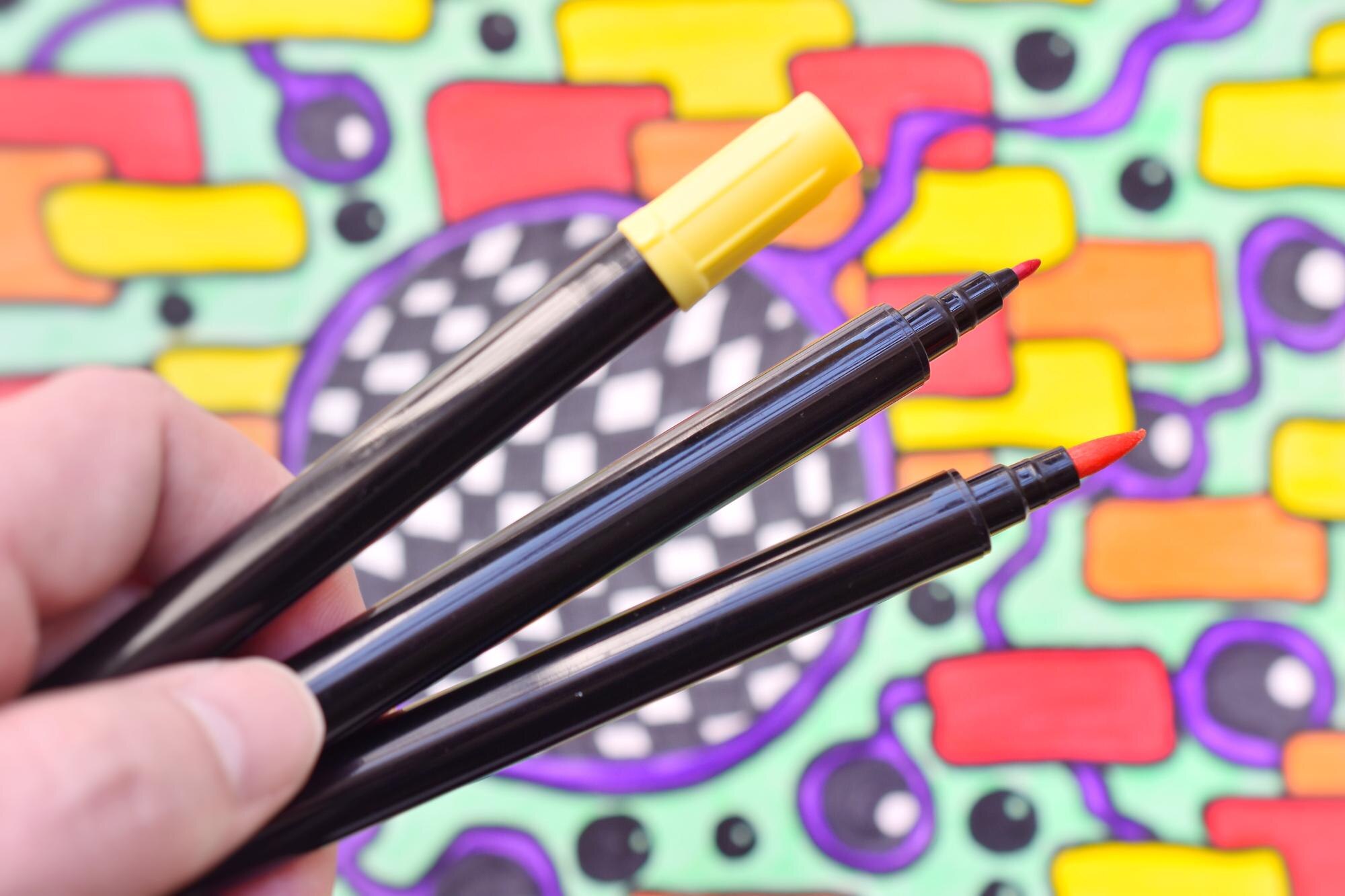 Ręka przycięta trzymająca długopisy na końcówce filcu przeciwko rysunkowi