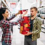 Młoda para kupuje patelnie w supermarkecie. Klienci płci męskiej i żeńskiej na rodzinne zakupy. Mężczyzna i kobieta kupują towary do domu