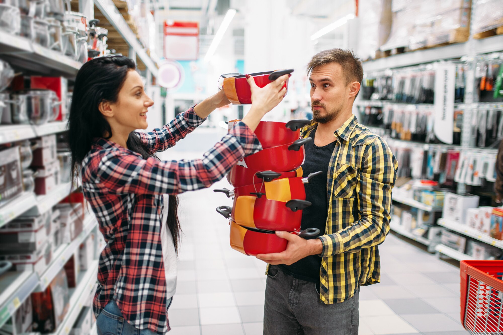Młoda para kupuje patelnie w supermarkecie. Klienci płci męskiej i żeńskiej na rodzinne zakupy. Mężczyzna i kobieta kupują towary do domu
