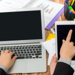 Biznesmen pisania na laptopie i wskazując tabletkę