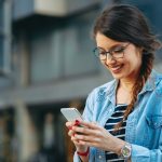 Młoda kobieta czytająca wiadomość na telefonie w mieście