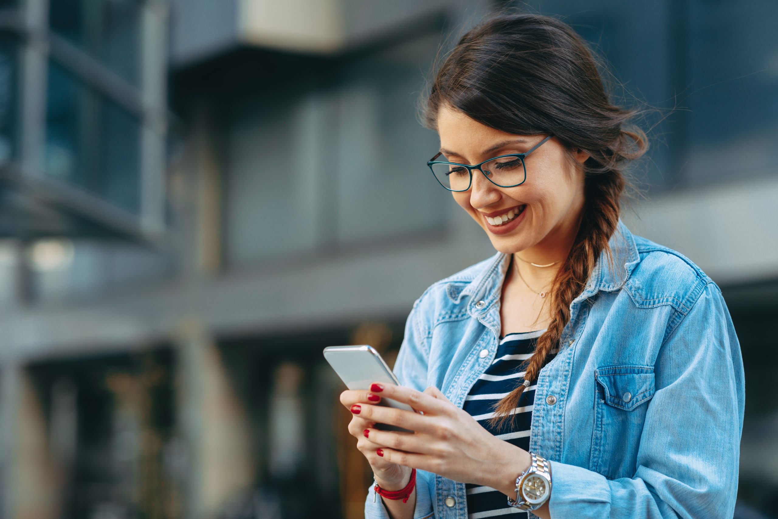 Młoda kobieta czytająca wiadomość na telefonie w mieście